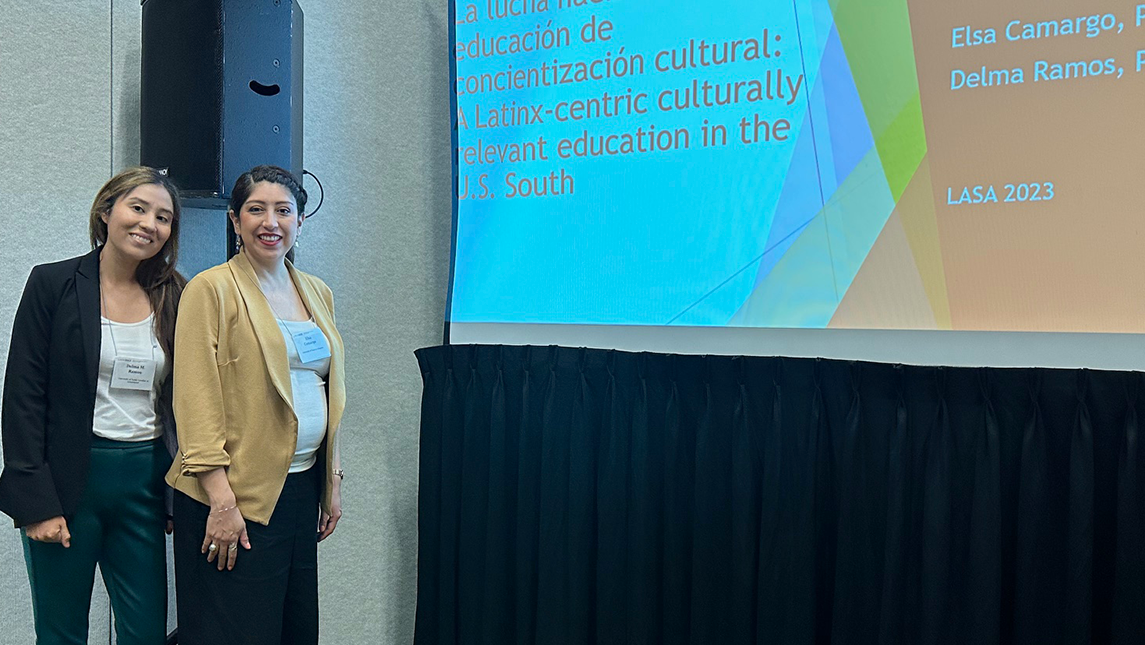 Dr. Delma Ramos, left, and Dr. Elsa Camargo, right, stand beside a screen with their presentation displayed